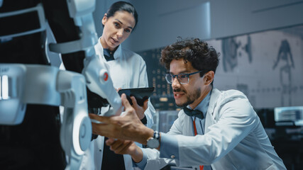 In Robotics Development Laboratory: Chief Female Engineer and Top Male Scientist Work on a Bionics Exoskeleton Prototype. Designing Powered Exosuit to Help Disabled People, Hard Labor Workers