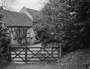 old house in the woods through a five bar gate