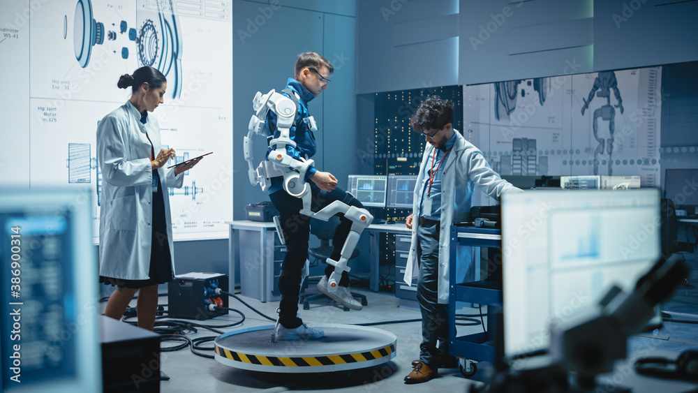 Leinwandbilder In Robotics Development Laboratory: Engineers and Scientists Work on a Bionics Exoskeleton Prototype with Person Testing it. Designing Wearable Exosuit to Help Disabled People, Warehouse Workers