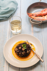 Black rice with shrimps and cremy pumpkin soup in a white plate