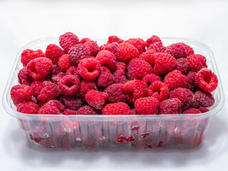 Plastic bowl of ripe red raspberries on a white background