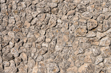 An uneven wall of decorative stacked cobblestones. Medieval background decorative insert