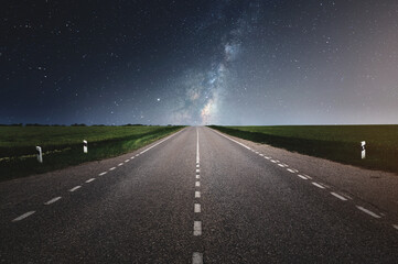 Straight asphalt country road under clear night sky with stars and milky way in summer