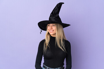 Young woman with witch costume over isolated background looking side