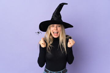 Young woman with witch costume over isolated background celebrating a victory in winner position