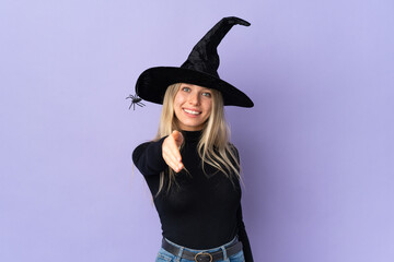 Young woman with witch costume over isolated background shaking hands for closing a good deal