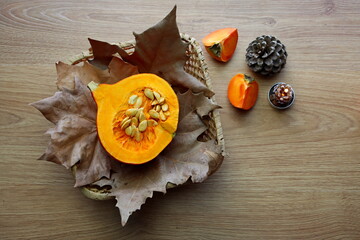 A cutaway hokkaido pumpkin lies on autumn leaves in a wicker basket. Autumn still life with...