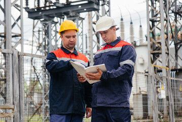 Two specialist electrical substation engineers inspect modern high-voltage equipment. Energy. Industry