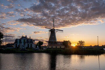 Fototapeta na wymiar Sunset at Rotterdam's Kralingse Plas, the typical Dutch windmill in the background