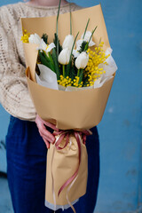 Bouquet of flowers in beige package in hands.
