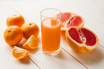Mix of fresh citrus fruits. Glass of juice and citrus with leaves on white background.