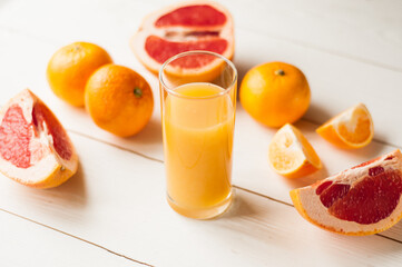 Mix of fresh citrus fruits. Glass of juice and citrus with leaves on white background.