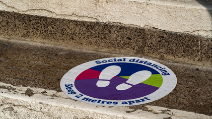 Colourful social distancing sticker on steps outside of a building