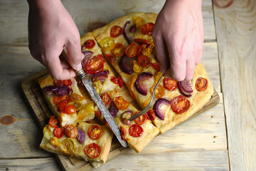 Selective focus. Homemade focaccia with cherry tomatoes and blue onions.