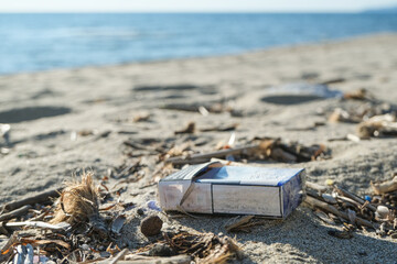Dirty cigarette pack trash discarded on sea coast ecosystem,environmental pollution issues