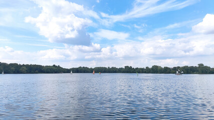 Several sailboats on a beautiful blue lake.