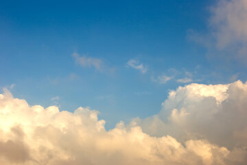 Soft and gentle, airy white and yellows clouds against the blue sky