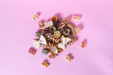 Italian pasta on a pink background. Different shape and different color. Copy space. Selective focus. Top view.