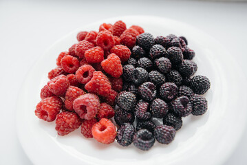 Black and red raspberry close-up on a white background. Healthy food, natural vitamins. Fresh berries