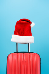 red santa hat on modern travel bag isolated on blue
