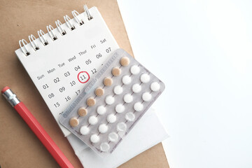 birth control pills , calendar and notepad on table 