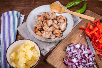 Ingredients for adobo pork with pineapple and bell pepper, roasted pork pieces in a bowl.