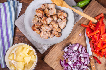 Ingredients for adobo pork with pineapple and bell pepper, roasted pork pieces in a bowl.