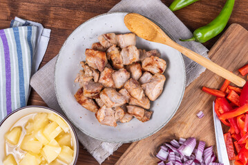 Ingredients for adobo pork with pineapple and bell pepper, roasted pork pieces in a bowl.