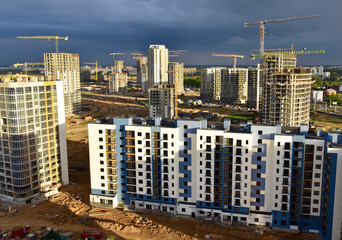 View on the large construction site at urban area. Tower cranes in action with machinery and builders. Multi-storey residential Building is being constructed use of crane. Pour of concrete in formwork