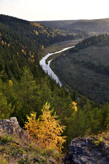 A bend of the Irgina River in a deep river valley among a bright autumn forest. In the foothills of the Western Urals, golden autumn.