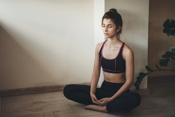 Fototapeta premium Caucasian woman in activewear is meditating on the floor while doing home gym exercises