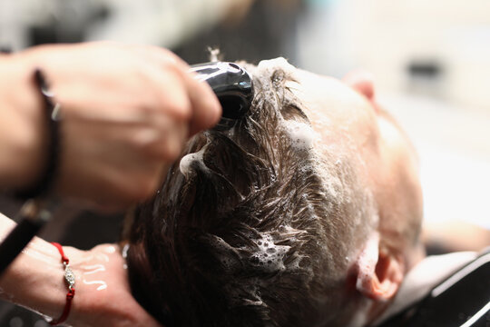 Master washes client's hair with shampoo in hairdressing salon. The list of services in the beauty salon concept