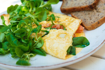 Two delicious poached eggs with salmon on toast served with mixed vegetables and lettuce in white ceramic plate