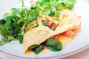 Two delicious poached eggs with salmon on toast served with mixed vegetables and lettuce in white ceramic plate