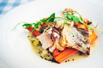 Delicious fillet of cod fish with carrots, leeks and mushrooms in white plate ready to be served