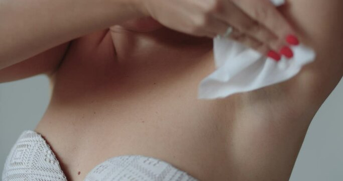 Woman gleaning armpit with wet wipes