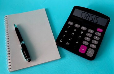 Notepad, pen, stethoscope on a blue background.The concept of medicine. the word crisis on a calculator, Notepad and pen on a blue background.The concept of crisis