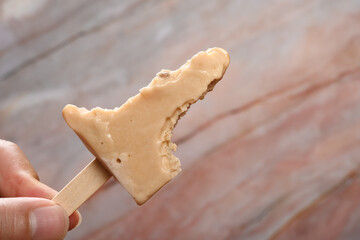 hand holding a mostly eaten tapioca milk tea flavor popsicle