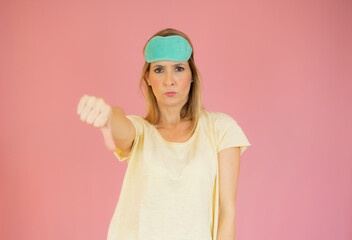 Portrait of displeased woman in nightwear who is showing thumb down