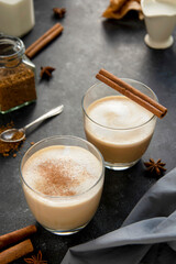 Hot chocolate with whipped cream in glass isolated with cinnamon stick, over dark background