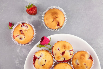Healthy dessert - strawberry muffins on white plate with fresh berries on grey concrete background
