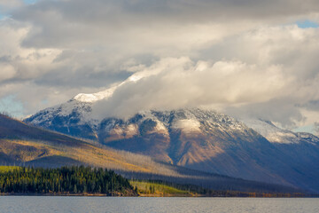 autumn landscape of majestic cloud enshrouded mountain in early morning with Lake McDonald in foreground, Glacier National Park, Montana