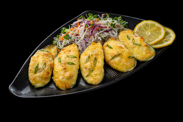 Delicious baked mussel Sushi appetizer including lemon, cabbage and carrot on black platet. Oyster, nutrition. Isolated on black background