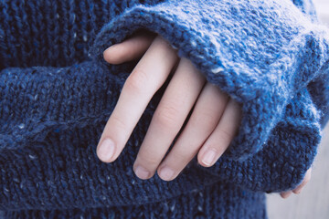 Woman in soft warm dark blue knitted sweater folded her hands. Autumn soon