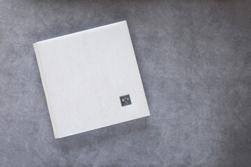 White photo book with leather cover. Stylish wedding or family photo album. Beautiful notepad or photobook with elegant openwork embossing on a grey background. Copy space