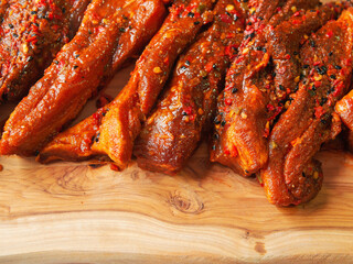 Raw uncooked fresh pork belly slices on a wooden cutting board. Red meat marinade with oil and herbs,