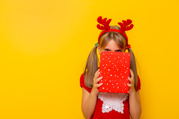 Little girl hiding behind Christmas present