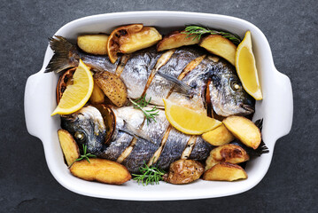 Baked gilt-head bream (dorade) fish with potatoes, herbs and spices.