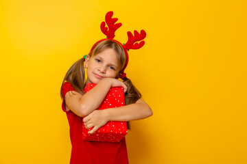 Little girl holding and hugging Christmas present