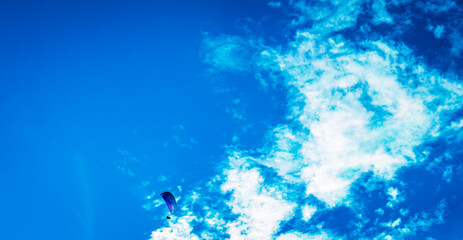Fototapeta na wymiar flying high in the sky, paraglider up in the air with a blue sky some clouds and copy space 